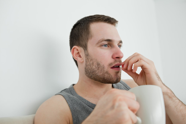 Мужчина пьет таблетки от акне
