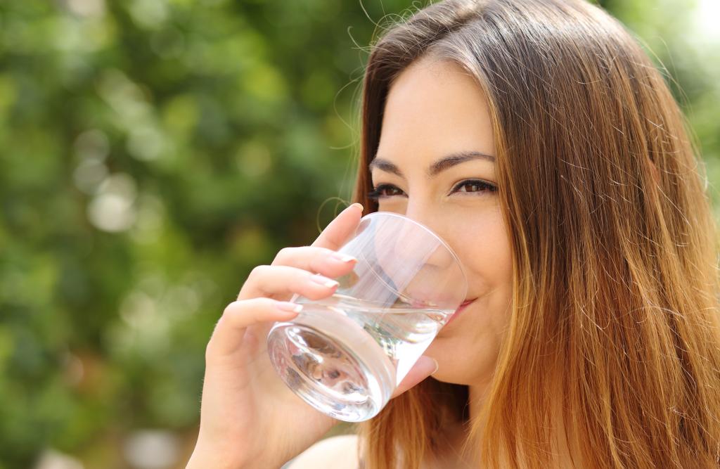 Девушка пьет воду.