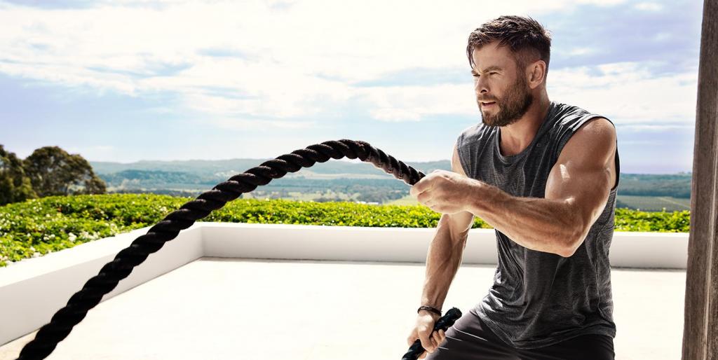 Мужчина тренируется с канатами.