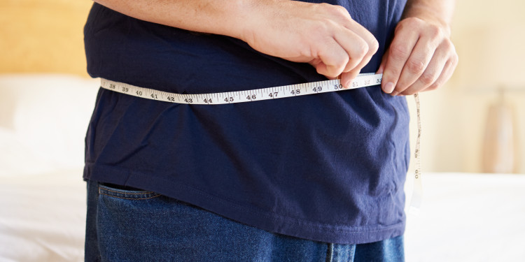 мужчина меряет объем талии